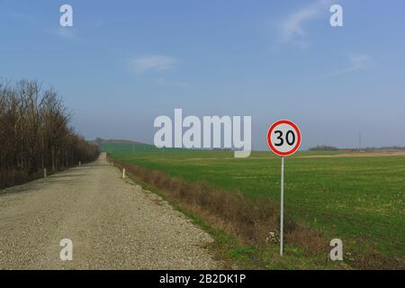 Das Tempolimit von Autokennzeichen 30 Kilometer pro Stunde liegt auf der Seite der Feldbahn entlang der Felder der grünen Triebe. Herbsttag Stockfoto