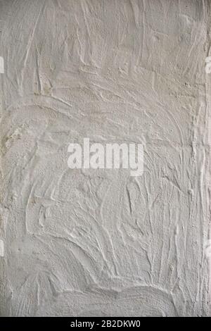 Weiße, strukturierte Wand mit wellenartigen Flecken. Texturhintergrund. Stockfoto