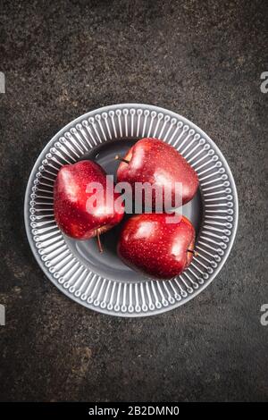 Drei reife rote Äpfel auf Platte. Draufsicht. Stockfoto