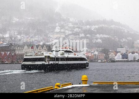 Winter in Bergen, Norwegen. Stark schneit. Blick vom alten Hafen der Stadt, Vaagen. Hanseatische Architektur der UNESCO in Bryggen. Passagier mit hoher Geschwindigkeit Stockfoto