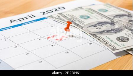 Roter Stift markiert am 15. April für den Steuertag, wobei die Dollars auf den Kalender 2020 fallen. Stockfoto