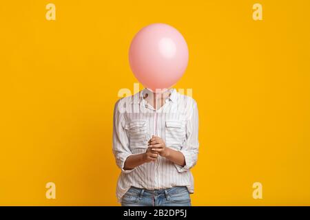 Unerkennbares Black Girl Versteckt Sich Hinter Pink Balloon Stockfoto