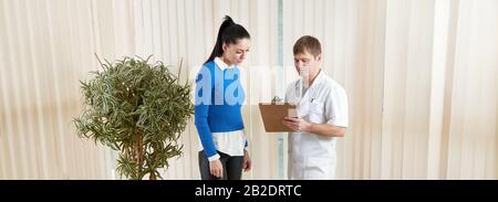Arzt zeigt weiblichen Patienten ihre medizinischen Testergebnisse im Korridor Stockfoto