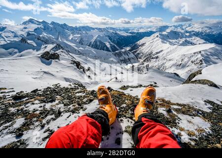 Blick vom Gipfel der Geierspitze, Beine mit Skischuhen vor einem schneebedeckten Bergpanorama, Wattentaler Lizum, Tuxer Alpen, Tyrol Stockfoto