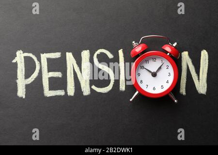 Inscription Pension mit Wecker auf schwarzem Hintergrund, Draufsicht Stockfoto