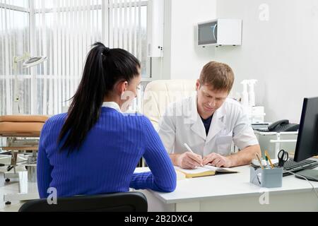 Arzt berät junge Frau in seinem Büro Stockfoto