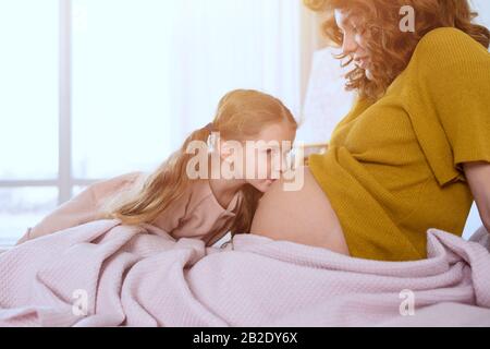 Schwangere Mutter spielt mit ihrer Tochter. Familienkonzept, Freude und Schwangerschaft Stockfoto