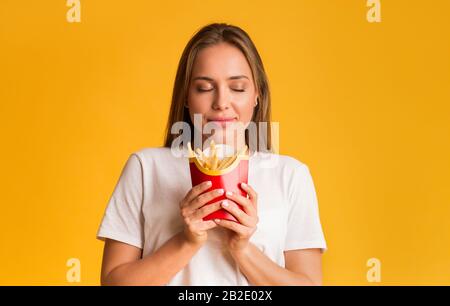 Porträt einer zufriedenen jungen Frau mit pommes frites in den Händen Stockfoto