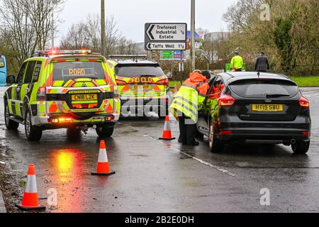 NANTGARW, IN DER NÄHE VON CARDIFF, WALES - FEBRUAR 2020: Verkehrsbeamte helfen einem Autofahrer nach einer Straßensperrung aufgrund von Überschwemmungen in Nantgarw nahe Cardiff Stockfoto