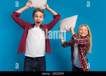 Verspielter Kleiner Junge Und Mädchen, Die Mit Kopfkissen In Camera Kämpfen Stockfoto