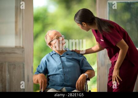 Lächelnder älterer Mann, der mit einer jungen Krankenschwester spricht Stockfoto