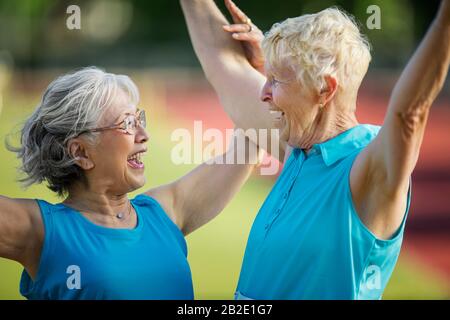 Zwei ältere Freunde feiern das Überqueren der Ziellinie bei einer Leichtathletikveranstaltung Stockfoto