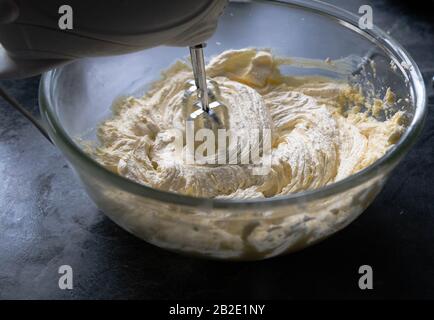 Eine Schüssel Butter und Zucker, die zusammen mit einem Handschwirl gecremt werden. Stockfoto