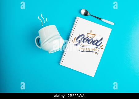 Blauer Kaffeebecher auf blauem Hintergrund mit dem Text Guten Morgen Stockfoto