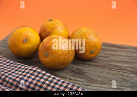 Einige Blutorangen auf Holzbrett und orangefarbenem Hintergrund mit Platz für Texte Stockfoto