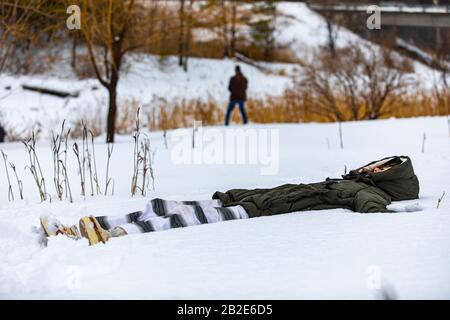 Das Mädchen, das auf dem Schnee liegt und eine Yoga-Übung macht. Die im Schnee liegende Frau, die meditiert, stärkt ihre Beziehung zur Natur Stockfoto