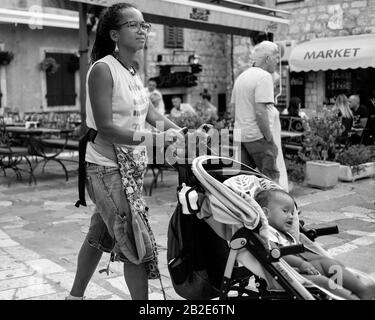 Kotor, Montenegro, 22. September 2019: Frau mit Baby, die in der Altstadt von Kotor die Straße hinunter läuft Stockfoto