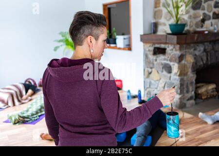 Eine Frau, die eine blaue Zierlampe in der Hand hält. Eine Frau in einer rosafarbenen Jacke, die ein blaues dekoratives kerzenähnliches Objekt in der Hand hält Stockfoto