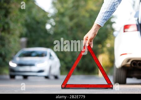 Rotes Dreieck eines Autos auf der Straße. Auto Warndreieck auf der Straße  gegen die Stadt am Abend Stockfotografie - Alamy