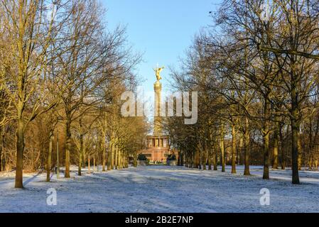 Abnehmende perspektivische Ansicht von schneebedeckenden Pfaden und Bäumen ohne Blätter im Tiergarten und Hintergrund der Siegessäule in Berlin, Deutschland. Stockfoto