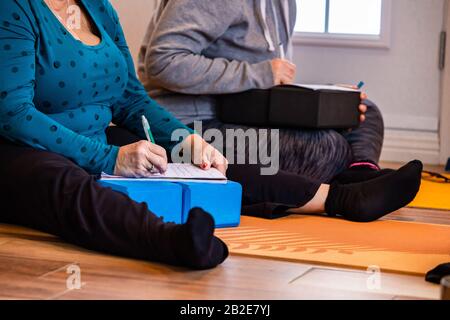 Das Ehepaar, das während des Yoga-Kurses Notizen macht. Die studierenden Yoga-Leute, indem sie Notizen auf einem Notizblock machen. Ein schreibender Mann und eine Frau Stockfoto