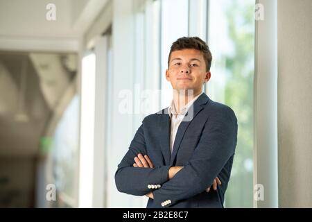 Porträt eines selbstbewussten jungen Mannes im Sportmantel im Geschäftsbetrieb Stockfoto