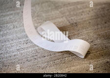 Hinzufügen von Papierband aus der Maschine, das auf dem Teppichboden gesammelt wurde Stockfoto