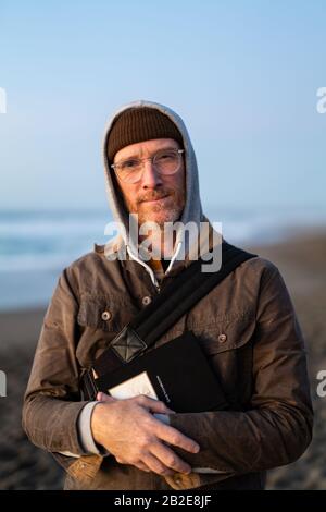 Porträt des reifen Mannes, der die Kamera am Strand sieht Stockfoto