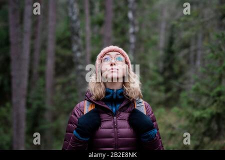 Porträt einer Frau, die im Winter in einem Wald zum Himmel blickt Stockfoto