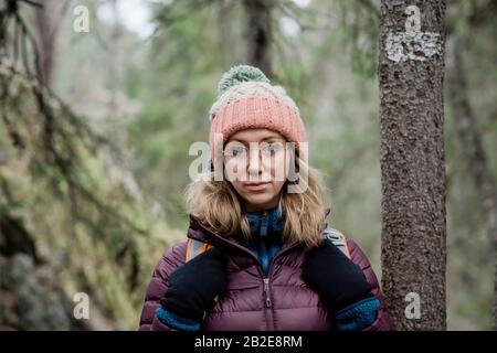 Porträt einer Frau, die im Winter alleine durch einen Wald in Schweden wandert Stockfoto