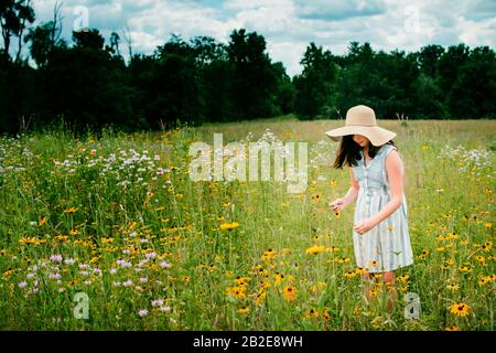 Mädchen trägt einen Floppy Sun hat pflücken Blumen in Süd-Michigan Stockfoto