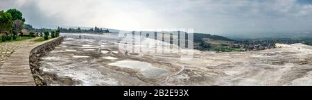 Ein Pfad in einem kleinen Park mit Aussichtsplattform auf dem weißen Pamukkale Berg in der Nähe von Travertinen an einem Sommermorgen. Stockfoto