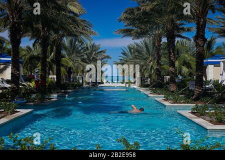 Mann im luxuriösen Pool von Palmen in Bahamas umgeben schwimmen Stockfoto