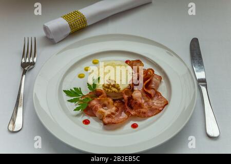 Warmer Ziegenkäse mit Honig und Speck auf einem weißen Gericht. Stockfoto