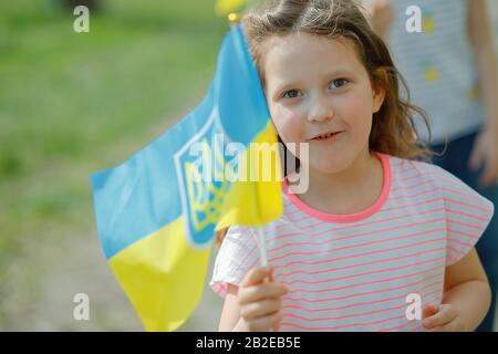 Die Flagge der Ukraine ist weiß blau mit einem Wappen in den Händen eines schönen Mädchens. Ein Kind hält eine Fahne am Unabhängigkeitstag der Ukraine und Flaggen da Stockfoto