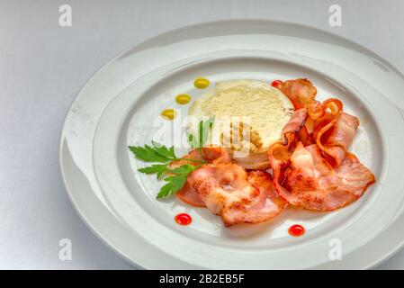 Warmer Ziegenkäse mit Honig und Speck auf einem weißen Gericht. Stockfoto