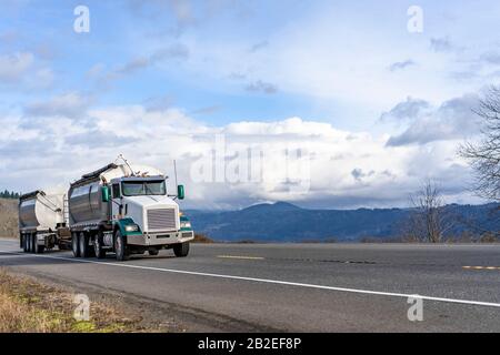 Industrietransport klassischer Kipper Big Rig Semi-Truck mit leistungsstarkem Dieselmotor, der schwere kommerzielle Fracht auf einem überdachten Massen-Halbweg transportiert Stockfoto