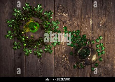 Fröhliche St. Patricks Tag Komposition. Shamrocks, Leprechaun Hut und Silbertopf auf einem alten rustikalen Holzhintergrund. St. Patrick's Day Feriensymbol. Top VI Stockfoto