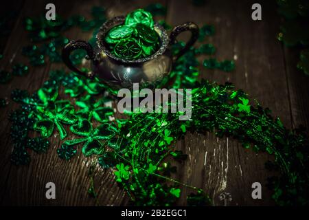 St. Patrick's Day Feriensymbol. Shamrock Kranz, Shamrocks und antike Silbertöpfchen mit Münzen auf einem alten rustikalen Holzhintergrund. Nahansicht Stockfoto