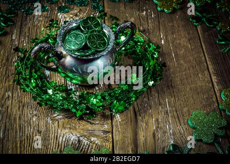 St. Patrick's Day Feriensymbol. Shamrock Kranz, Shamrocks und antike Silbertöpfchen mit Münzen auf einem alten rustikalen Holzhintergrund. Nahansicht Stockfoto