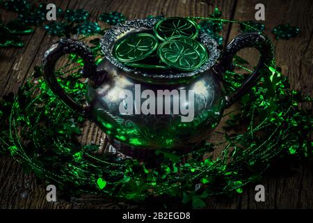 St. Patrick's Day Feriensymbol. Shamrock Kranz, Shamrocks und antike Silbertöpfchen mit Münzen auf einem alten rustikalen Holzhintergrund. Nahansicht Stockfoto