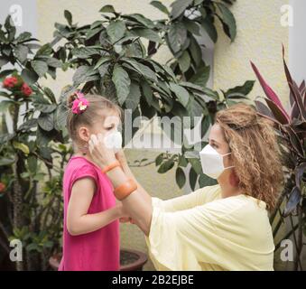 Frau und Tochter tragen eine Einwegmaske, um Virusinfektionen zu vermeiden. Schutz vor Coronavirus Stockfoto