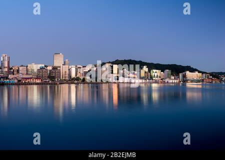 Wellington, neuseeländische Stadtgebäude und Skyline spiegelten sich bei Sonnenaufgang an einem perfekten Sommermorgen im Hafen wider. Wellington ist die Hauptstadt von NZ. Stockfoto