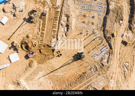 Pfahlfahrer und andere Industriemaschinen auf einer Baustelle. Baugrund im Bau. Luftbild Draufsicht Stockfoto