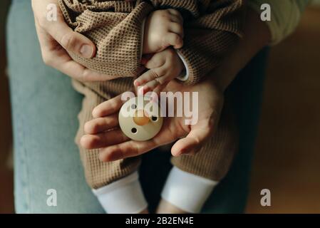 Baby hält einen Schnuller in den Armen seiner Mutter Stockfoto