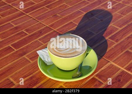 Hochwinkeliger Blick auf die Kaffeetasse auf dem Tisch - Latte Art bei Sonnenlicht Stockfoto