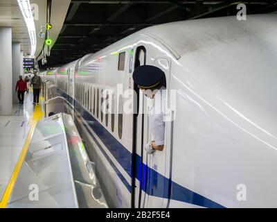 Tokio, Japan - 13. Oktober 2018: Der Leiter eines Shinkansen-Einschusszuges der Serie N700 überprüft den Bahnsteig vor der Abfahrt vom Bahnhof Tokio. Stockfoto