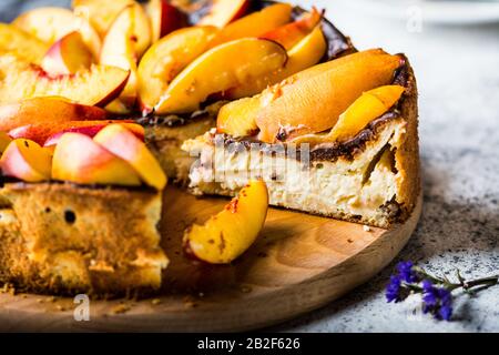 New York Cheesecake Mit Pfirsichen. Mascarpone Käsekuchen. Gesunde Ernährung. Dessert mit Früchten. Sommerkuchen. Stillleben von Lebensmitteln. Stück Kuchen Stockfoto