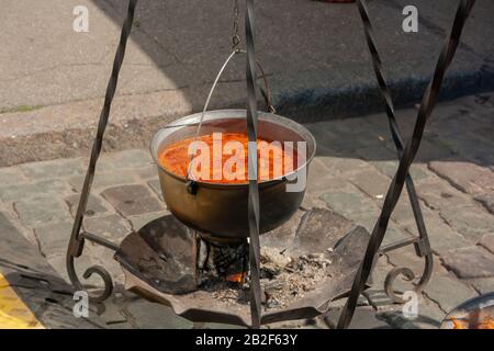 Kochen unter Feldbedingungen. Kochender Topf mit Suppe, die über dem Lagerfeuer hängt. Stockfoto