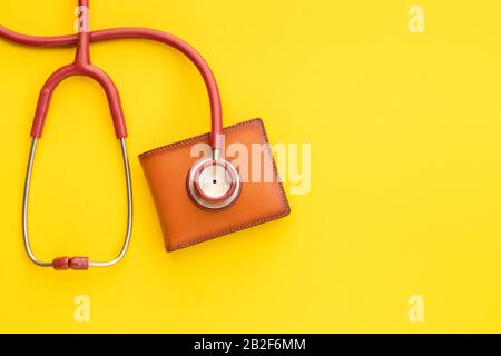 Schließen Sie das Stethoskop des Arztes und die neue lederbraune Männertasche auf gelbem Hintergrund. Budget für Gesundheitscheck oder Geld- und Finanzkonzept Stockfoto